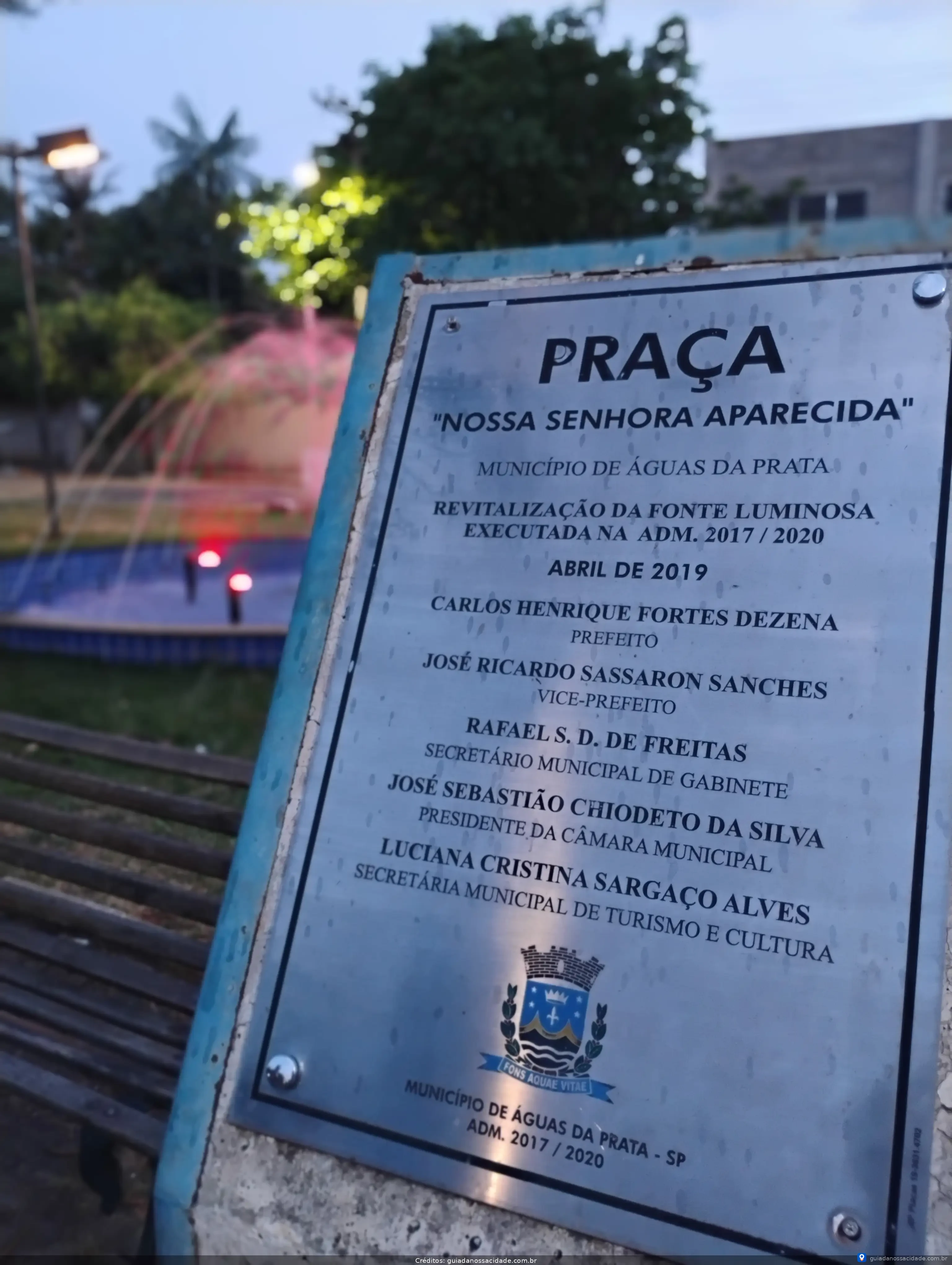Placa da Praça Nossa Senhora Aparecida com informações sobre a revitalização da fonte luminosa em Águas da Prata.