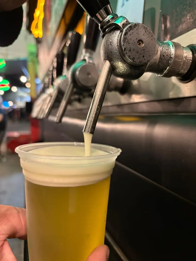 Copo plástico sendo preenchido com chope em torneira de cerveja.
