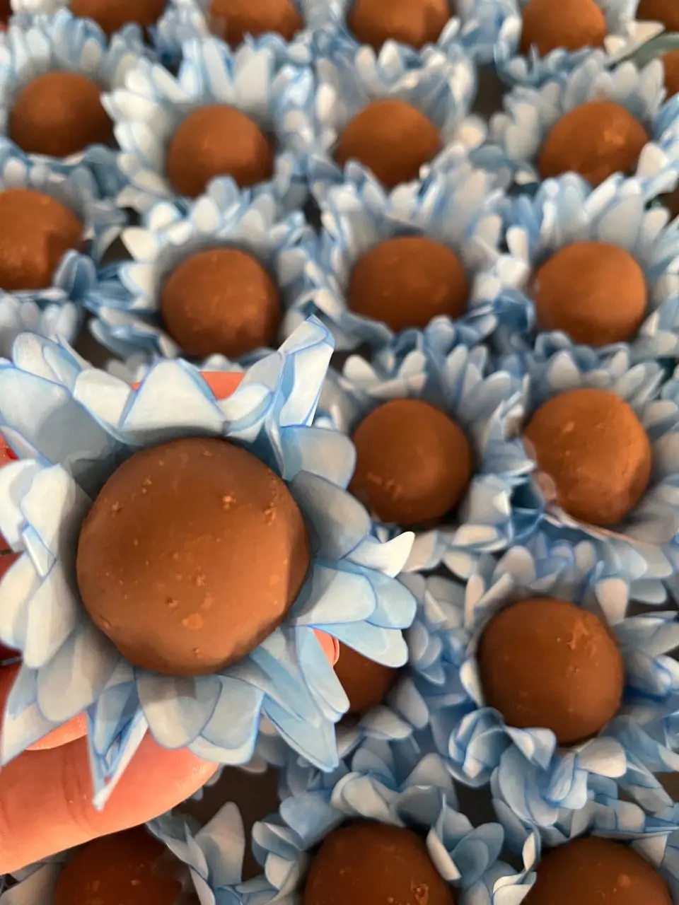 Doces de chocolate redondos sobre forminhas de papel azul.
