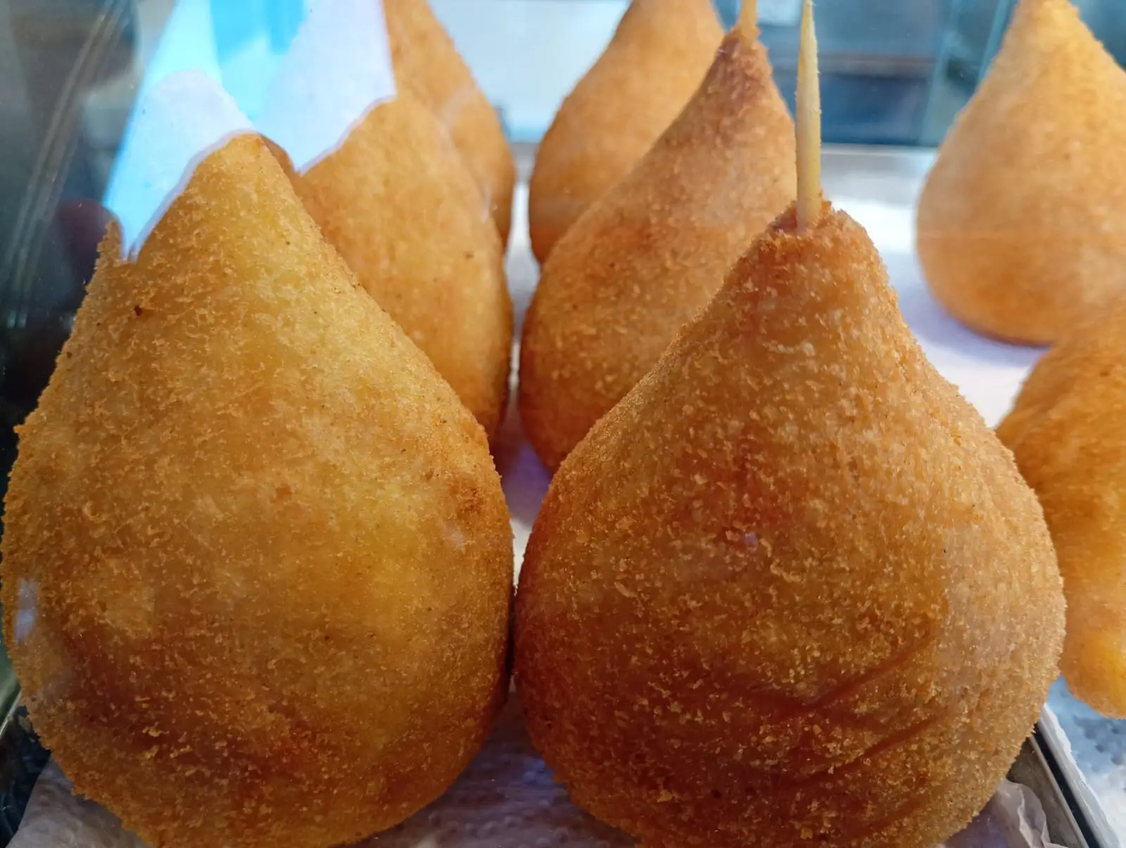 Coxinhas douradas em bandeja, algumas com palitos no topo.