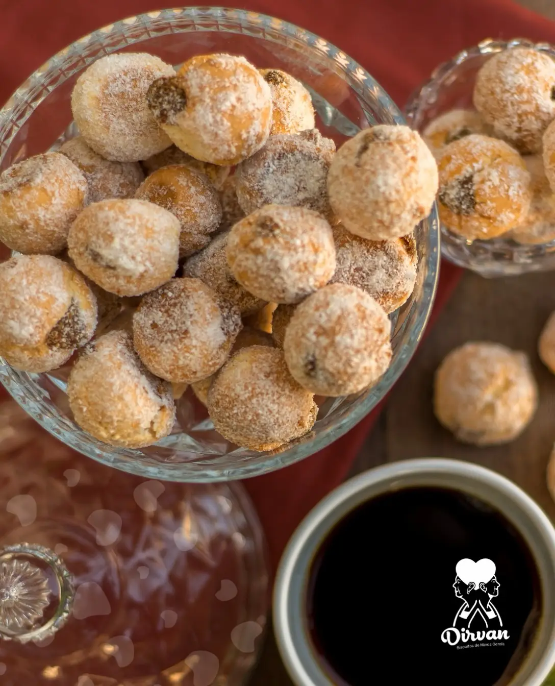 Potes de cristal com biscoitos de polvilho cobertos de açúcar ao lado de uma xícara de café preto.